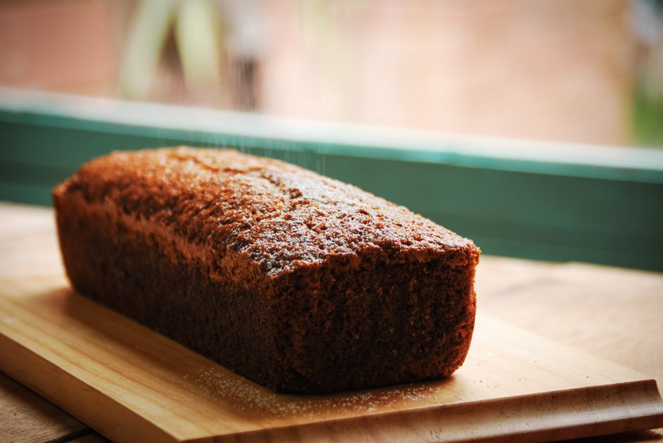 Closeup of sweet delicious fresh baked banana bread cake placed on wooden cutting board in kitchen